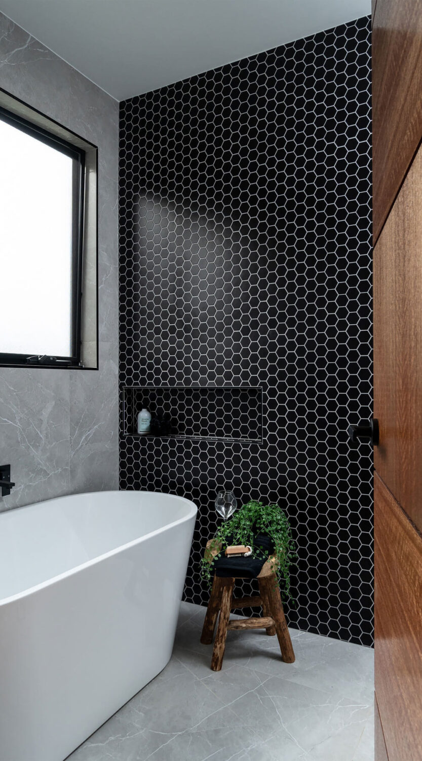 Hexagon pattern black and white wall tiles contrasted with gray marble floor and wall tiles.