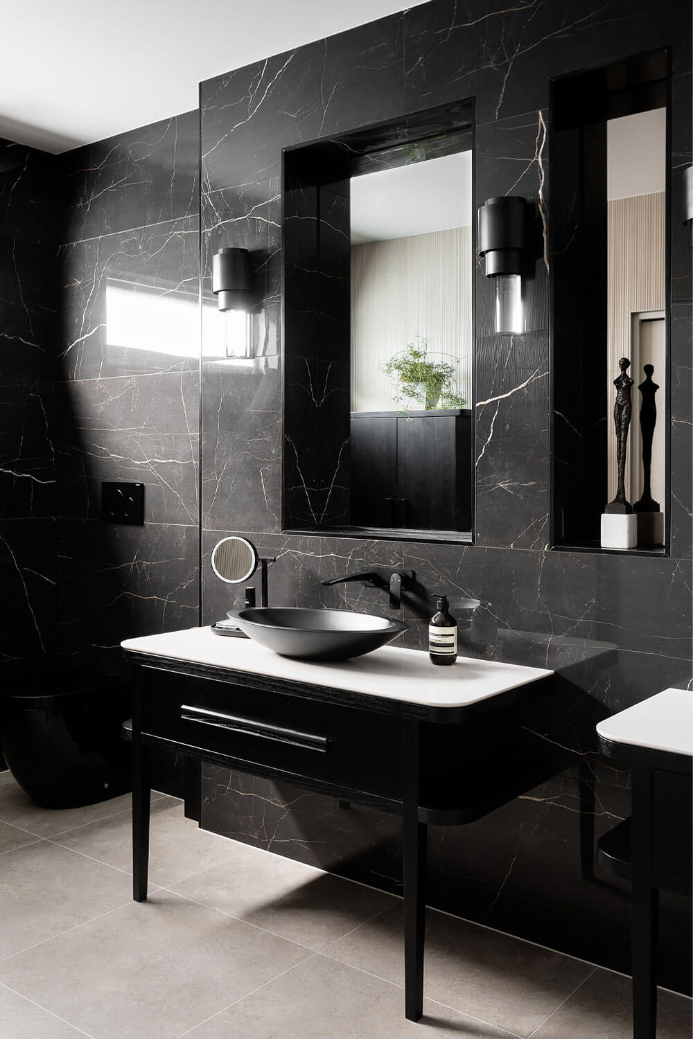 Gray marble wall tiles along with a black toilet and bathroom cabinets.
