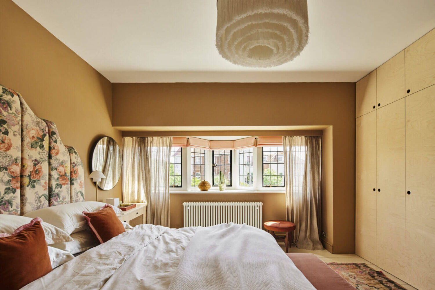 bedroom-floral-headboard-warm-wall-color-built-in-wardrobes-nordroom