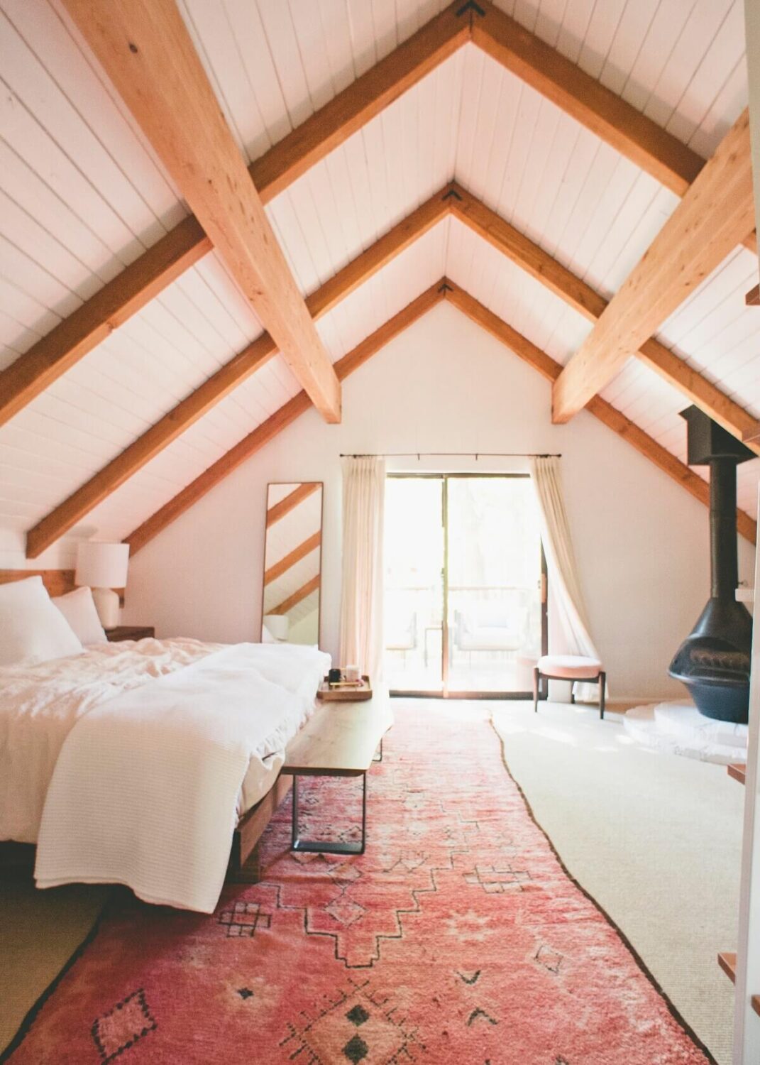 master-bedroom-sloped-ceiling-pink-rug-exposed-beams-nordroom