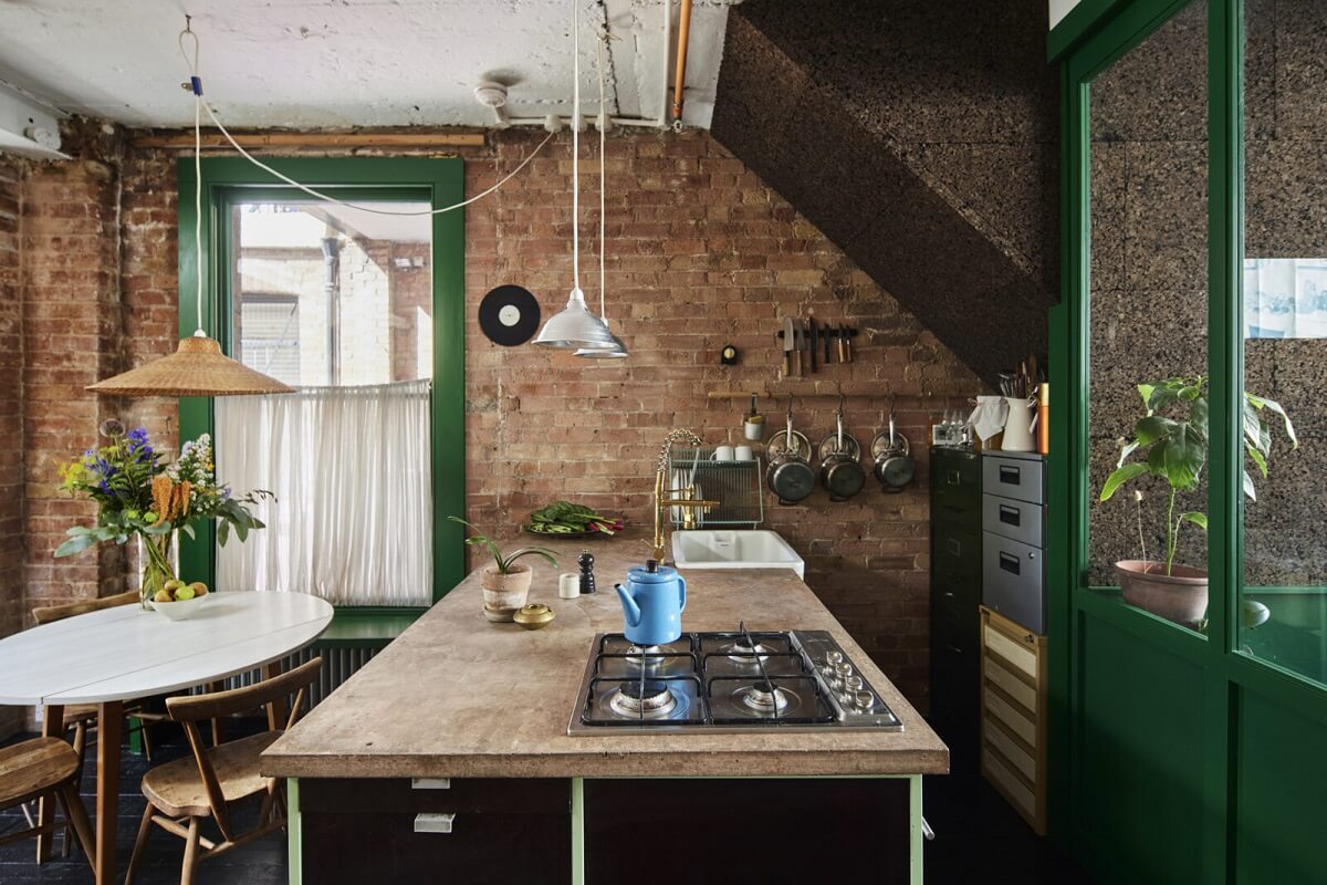 kitchen-brick-wall-island-round-dining-table-green-window-trims-nordroom