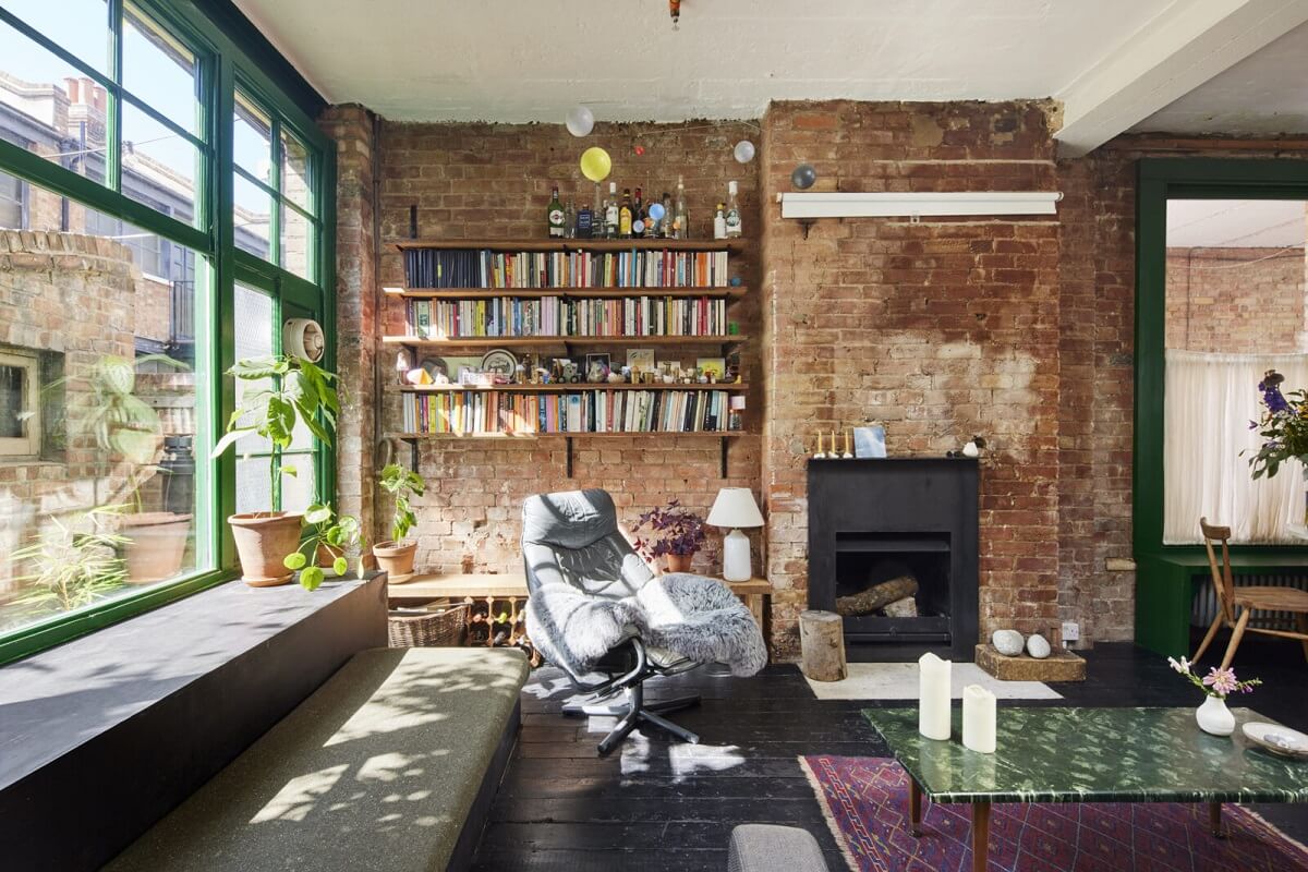 living-room-brick-walls-bookshelves-fireplace-dark-wooden-floor-green-window-trims-nordroom