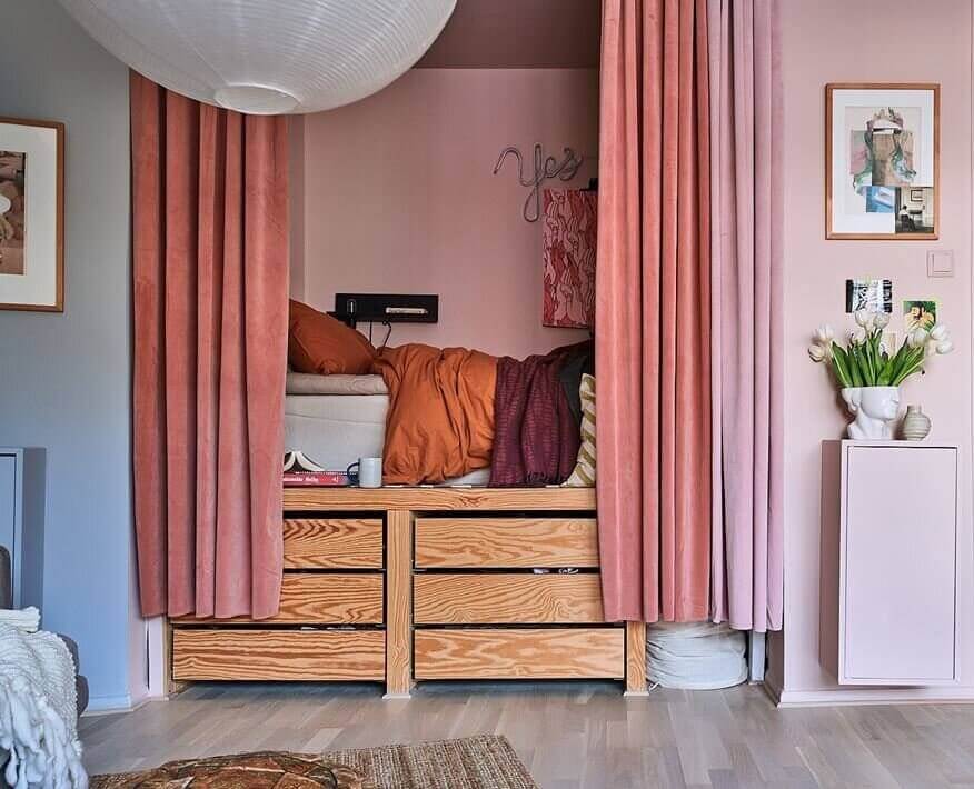 https://www.thenordroom.com/wp-content/uploads/2022/10/colorful-bed-nook-pink-curtains-storage-bed-nordroom.jpg