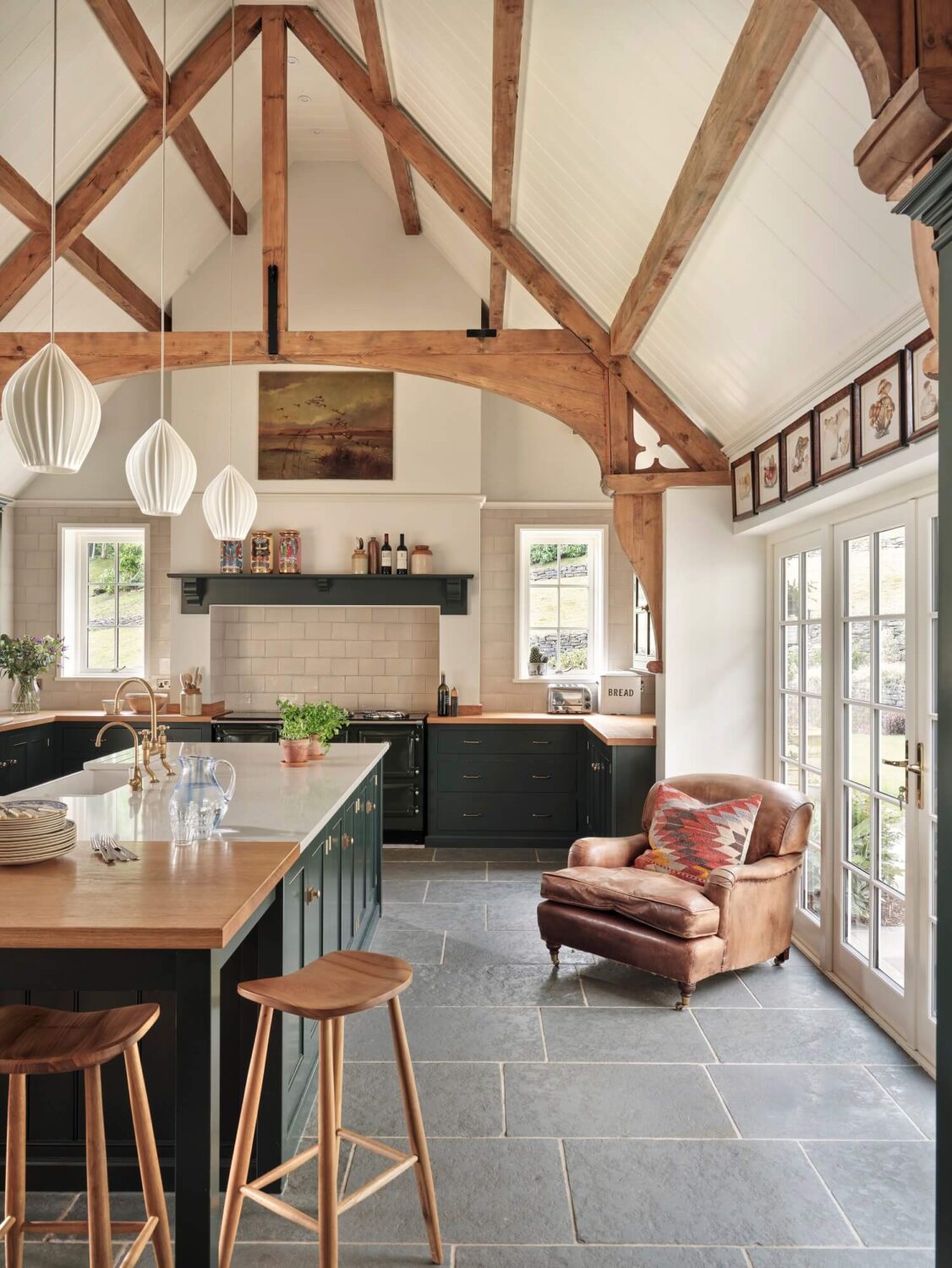 large-kitchen-island-flagstone-floor-leather-armchair-exposed-wooden-beams-devol-nordroom