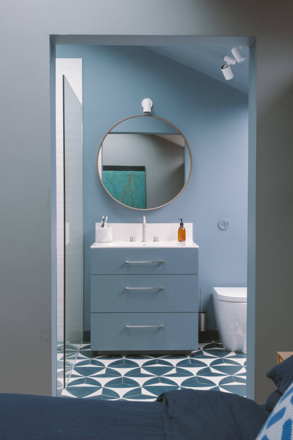blue-en-suite-bathroom-round-mirror-geometric-floor-tiles-nordroom