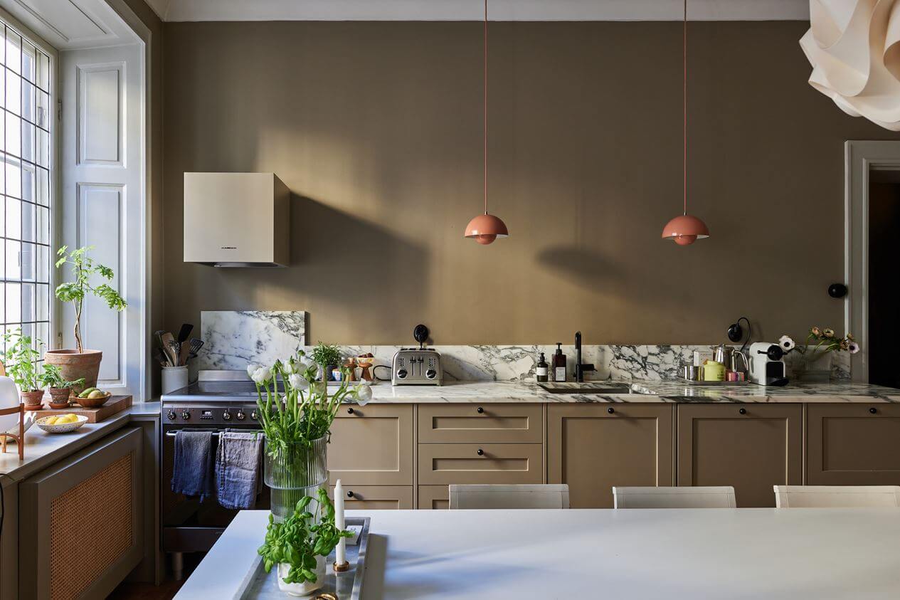 kitchen-dining-table-brown-walls-pink-pendants-marble-worktop-backsplash-nordroom