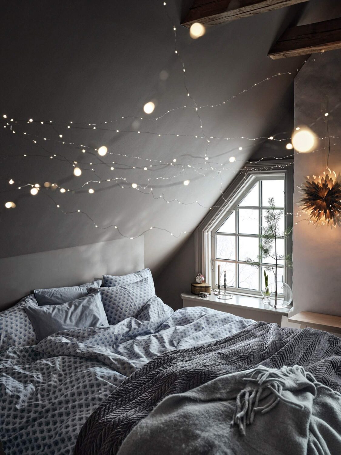 https://www.thenordroom.com/wp-content/uploads/2023/06/cozy-bedroom-string-lights-slanted-ceiling-nordroom-1125x1500.jpg