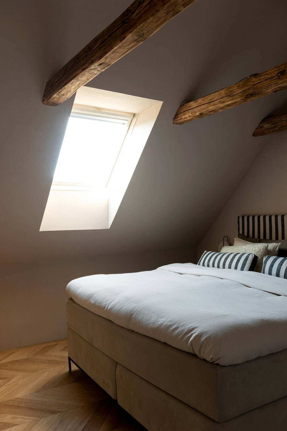 attic-bedroom-wooden-beams-striped-headboard-nordroom