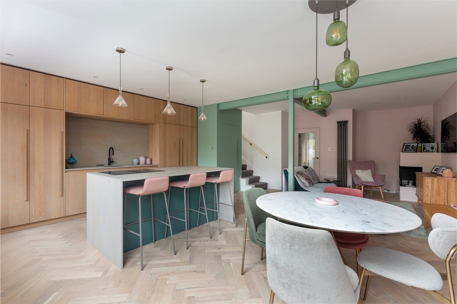 open-plan-living-kitchen-round-dining-table-kitchen-island-bar-green-accents-nordroom