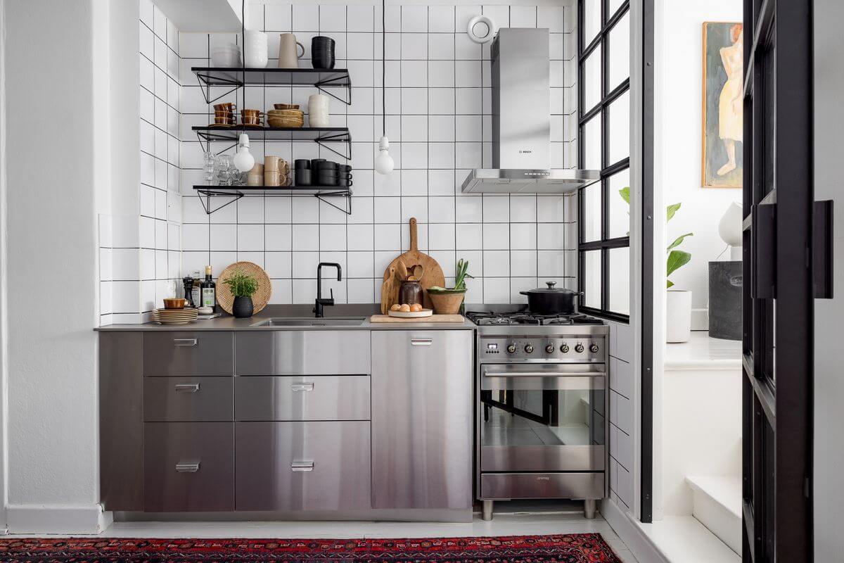 stainless steel kitchen with white tiles and pink rug