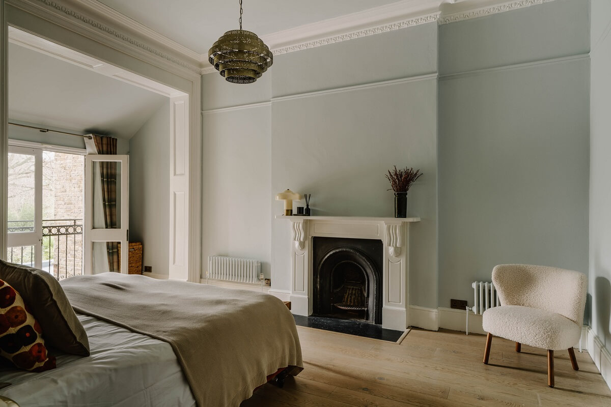 light blue bedroom with wooden floor and fireplace