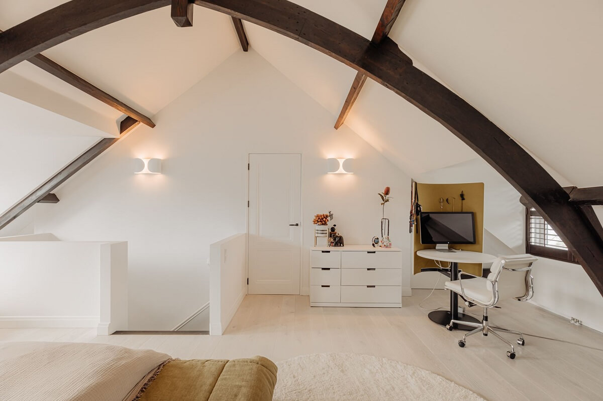 bedroom with exposed beams and small home office