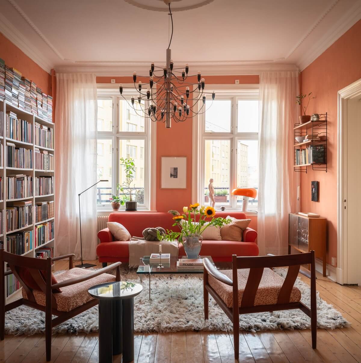 living room with orange pink terracotta shade on walls and bookshelves