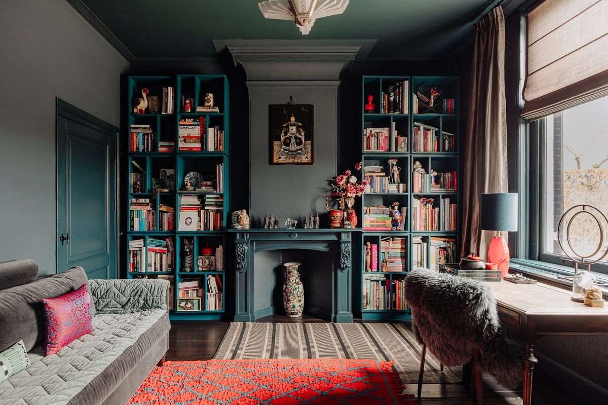 moody living roo with bookcases and blue fireplace