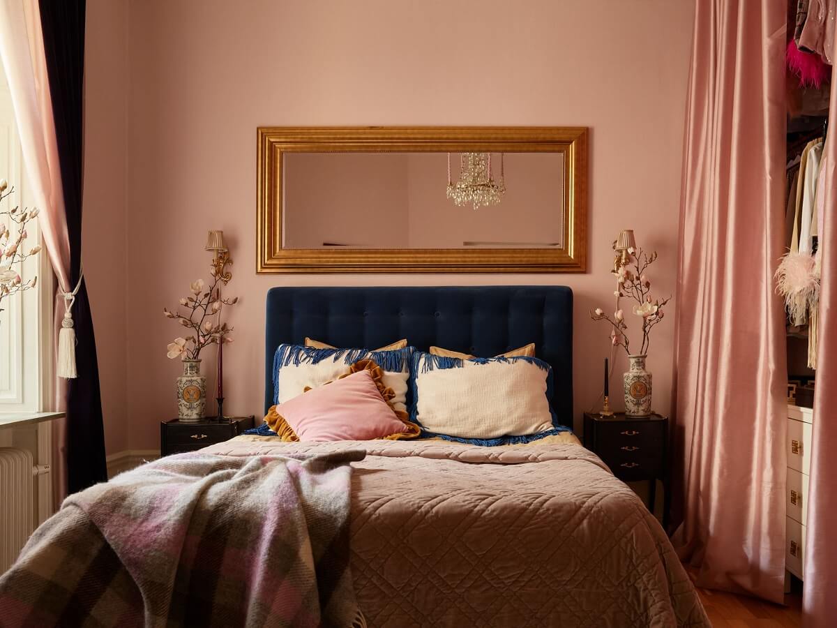 pastel-pink-bedroom-with-blue-velvet-bedframe-wardrobes-hidden-by-curtain-nordroom