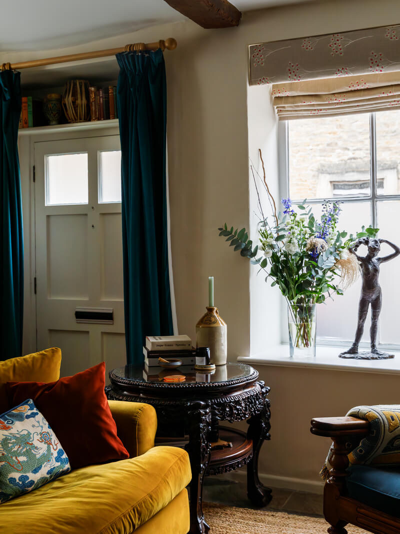 cottage living room with ochre yellow sofa and front door with curtains