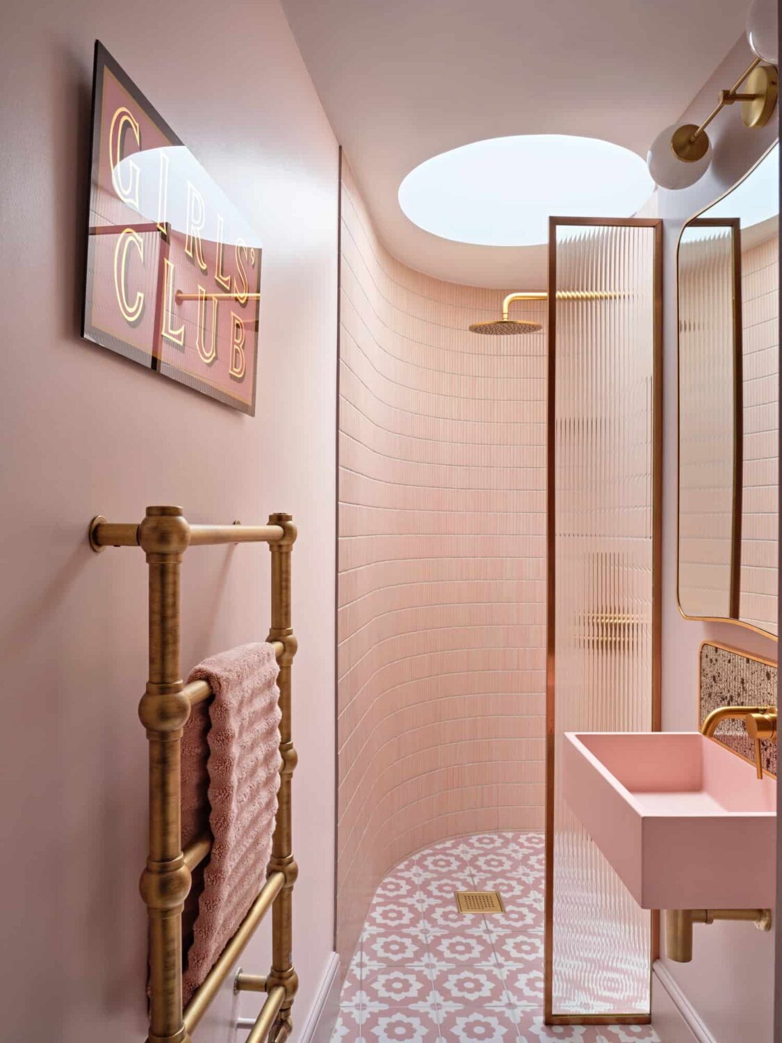 pink bathroom with rounded walk in shower and skylight