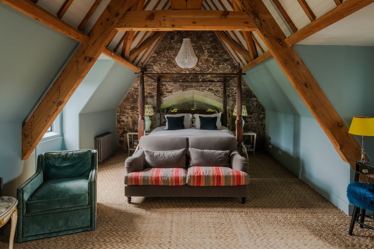A Charming Gothic-Style Home with Original Details 28 blue attic bedroom with wooden beams and stone wall nordroom