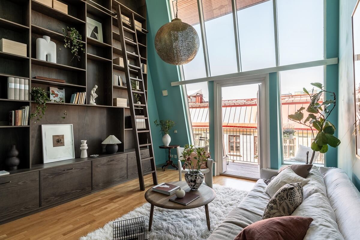 blue living room with double height ceiling and bookcases with ladder nordroom
