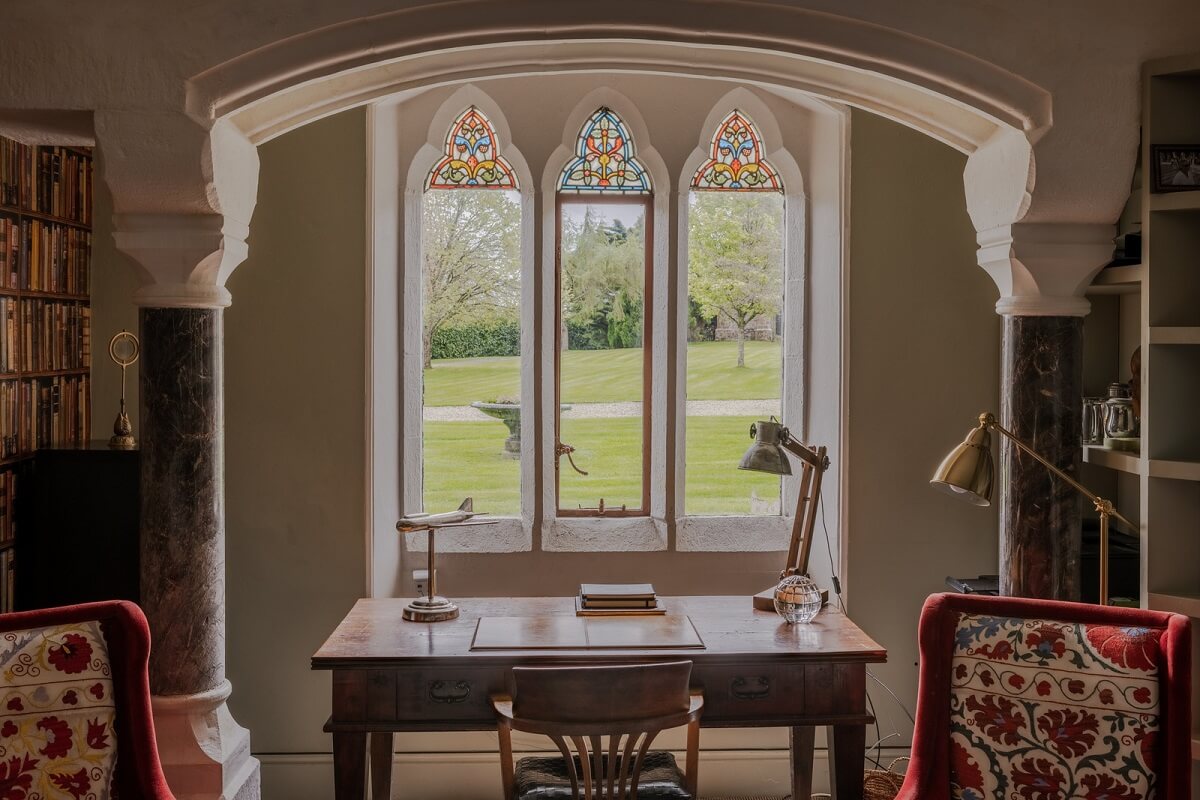A Charming Gothic-Style Home with Original Details 19 desk in front of window with stained glass nordroom