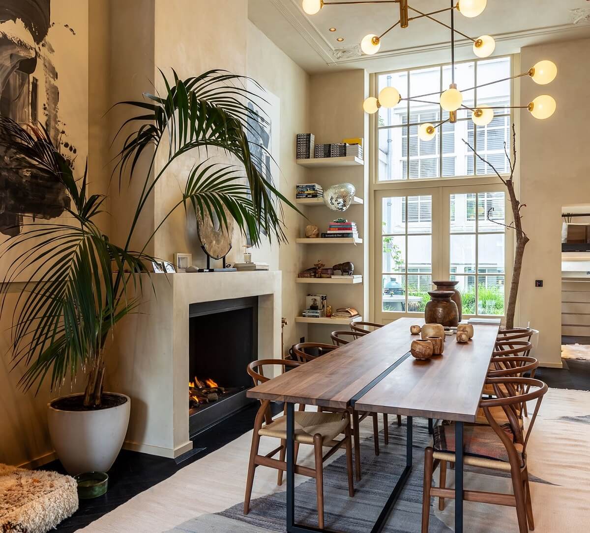 dining room with floor to ceiling window fireplace and large wooden table with wishbone chairs
