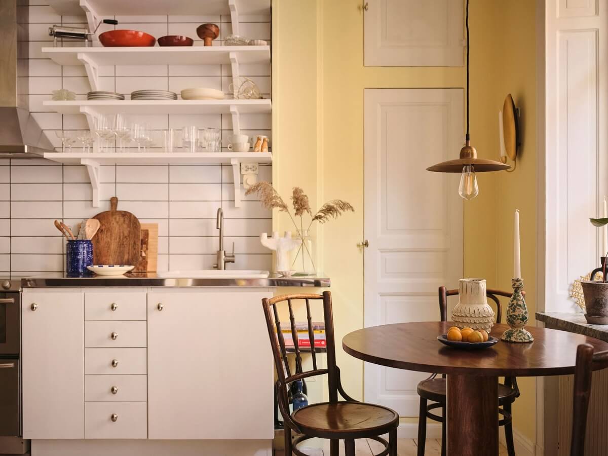 kitchen with white cabinets yellow walls and round wooden table nordroom