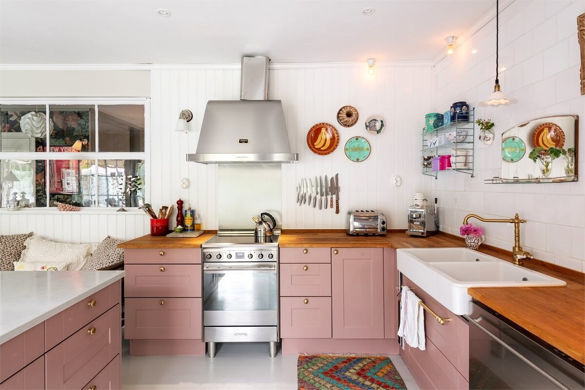 pink kitchen with wooden worktop and butler sink