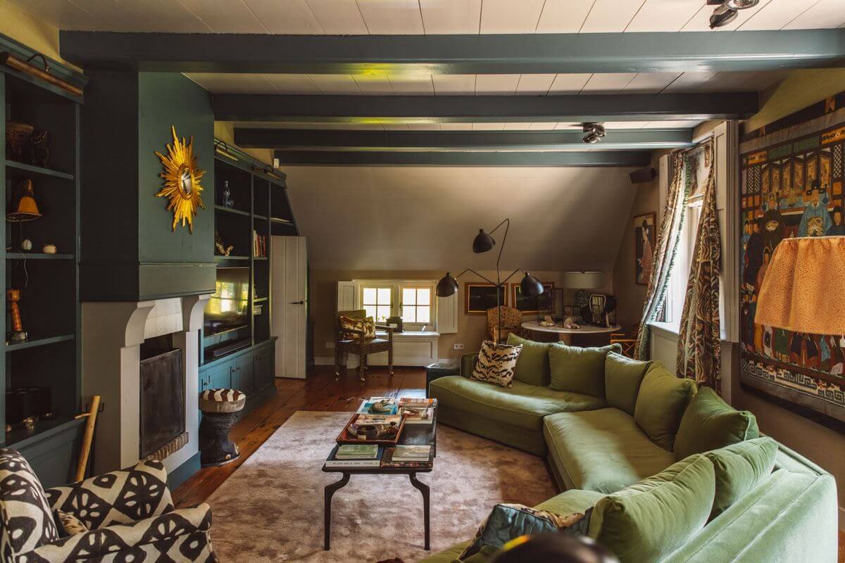 green living room with wooden beams and large velvet sofa