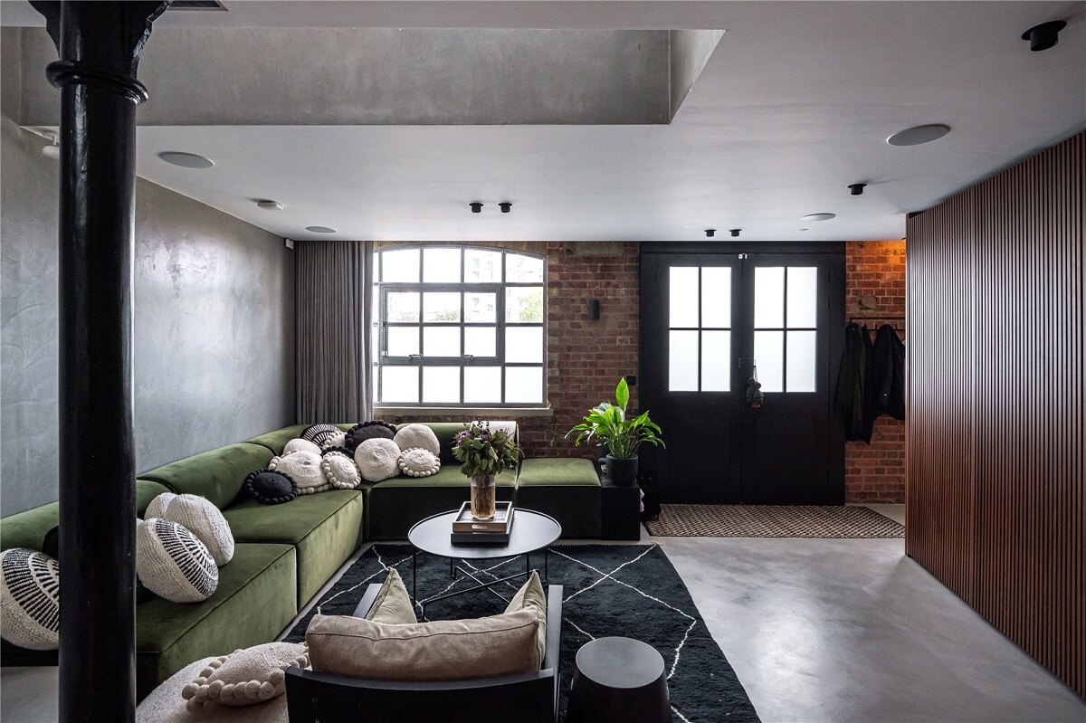 industrial living room with brick wall green corner sofa and wooden cabinets