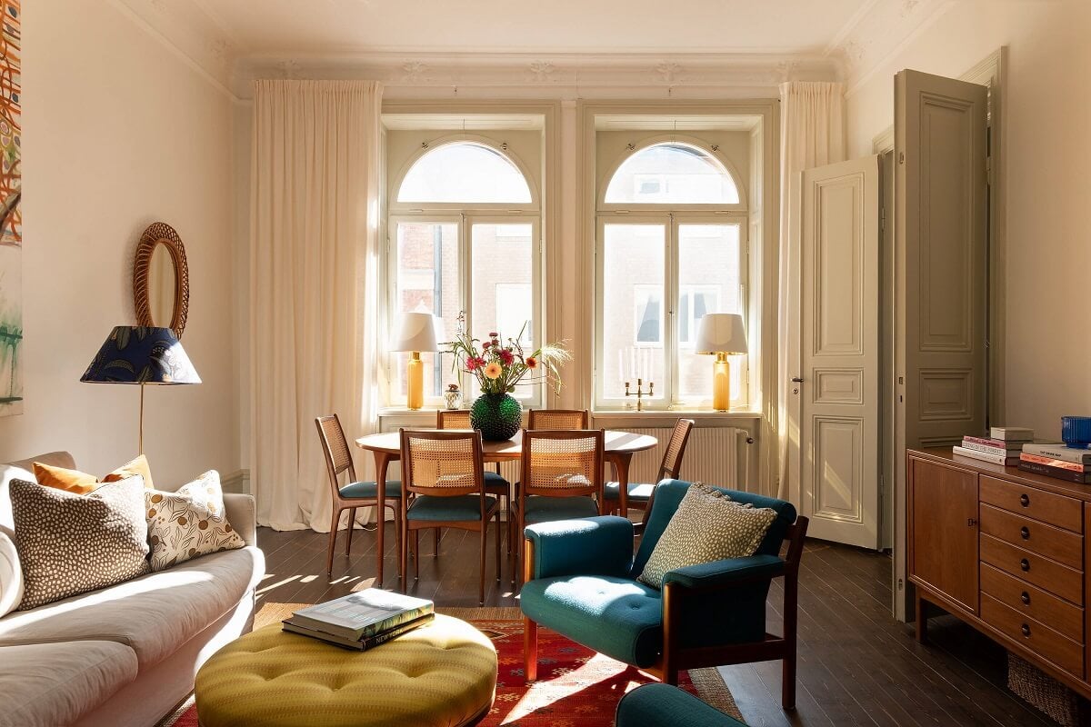 A Beautiful Turn-of-the-Century Apartment with Bold Color Accents 1 living room with arched windows and blue chair red rug