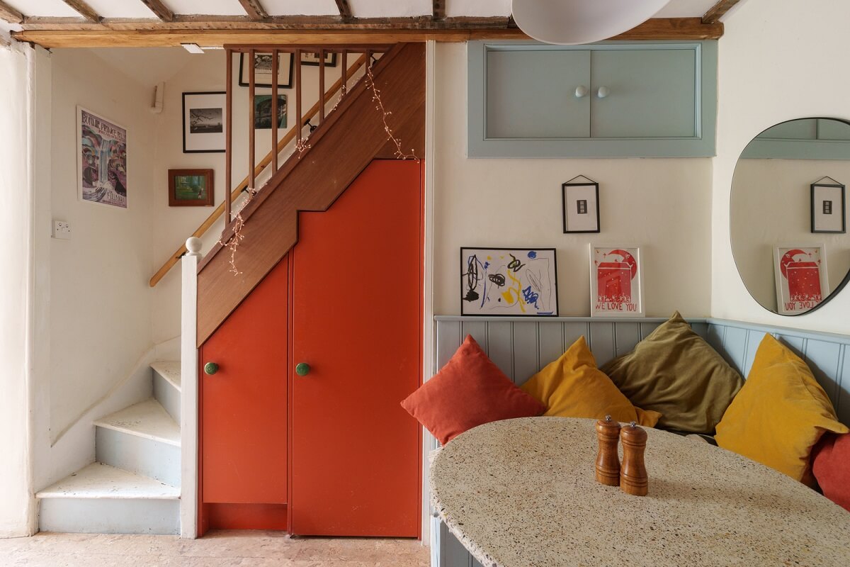 kitchen built in seating and orange cupboards under stairs