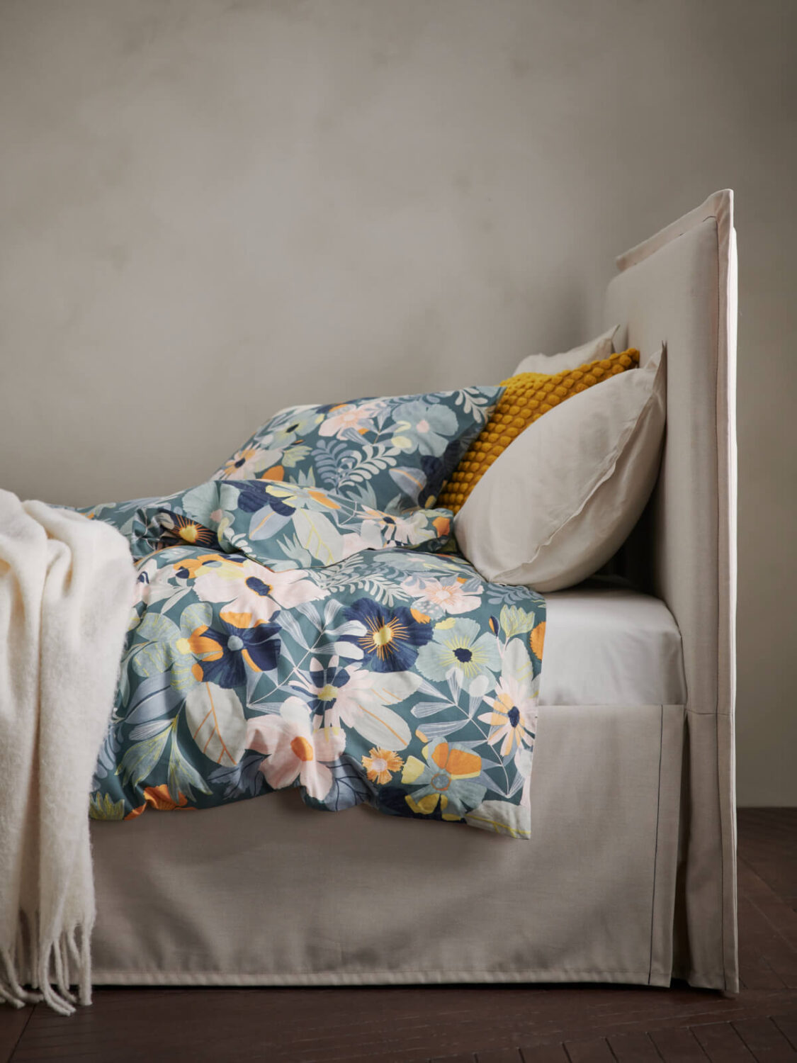 bed from the side with textured headboard and floral bedding