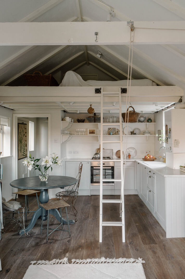 kitchen with open shelves round dining table and loft bed nordroom