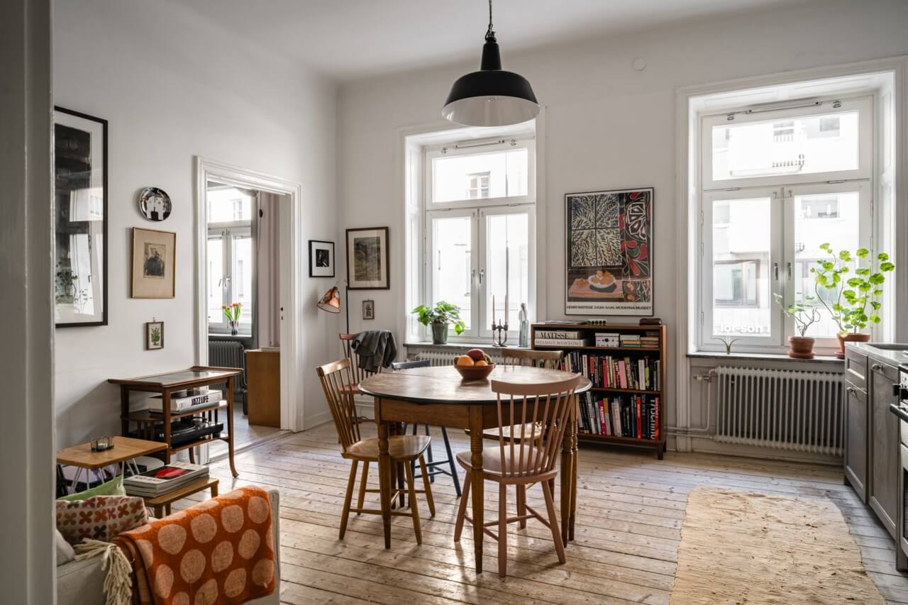 Muted Tones, Art, and Books in a Charming Stockholm Apartment 1 open plan living room and kitchen with a wooden table in the center