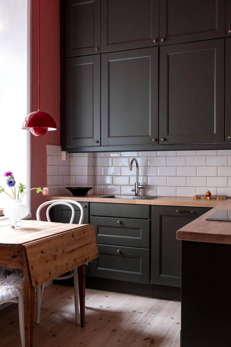 black kitchen cabinets pink wall wooden table
