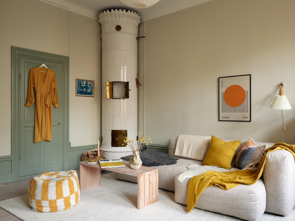 A Muted Color Palette and Smart Storage in a Small Stockholm Apartment 1 green joinery living room yellow color accents fireplace