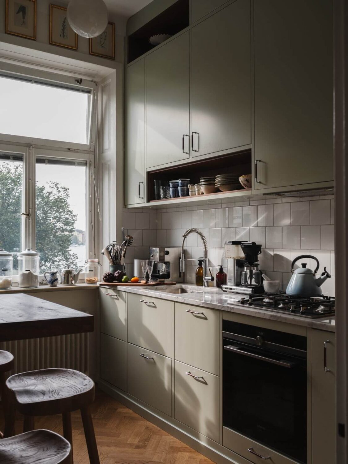 Gray Tones and Built-in Storage in a Charming Corner Apartment 10 small kitchen high bar table white backsplash tiles