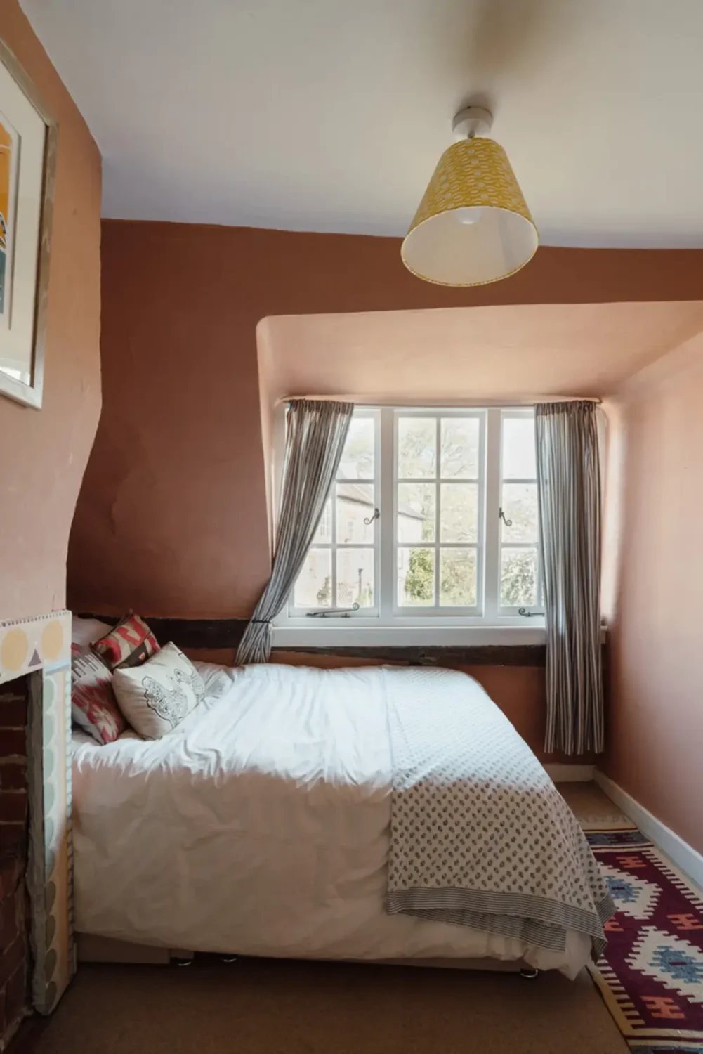 cottage bedroom with fireplace and earthy pink walls