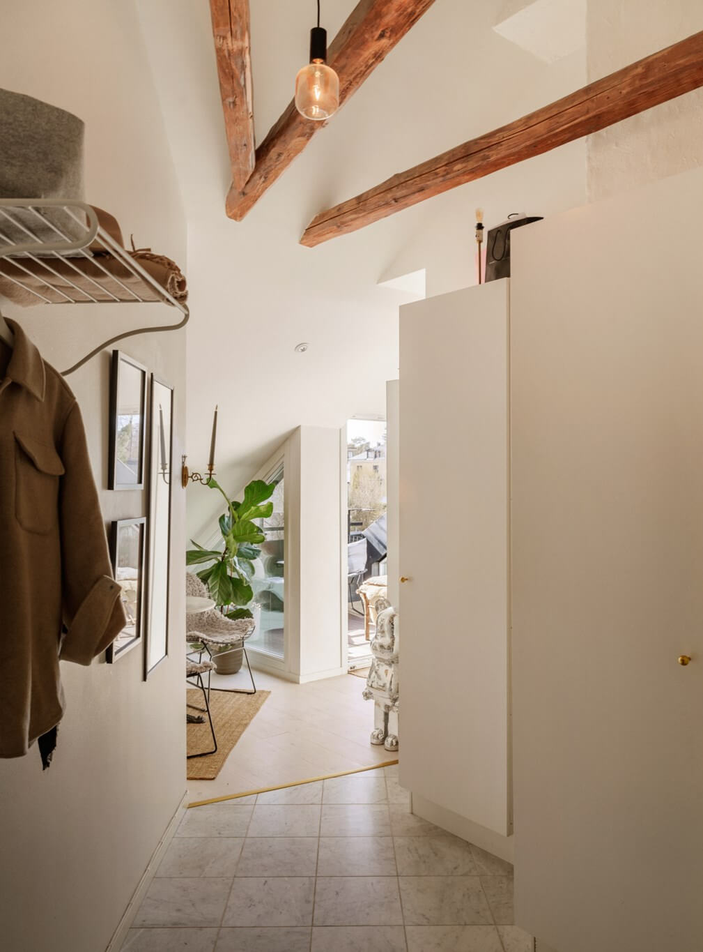 hall marble tiles exposed wooden beams A Bright Attic Apartment with Exposed Beams and a Roof Terrace