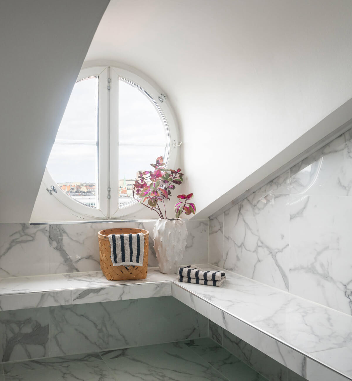 marble bathroom round window A Stylish Black and White Penthouse Apartment in Stockholm