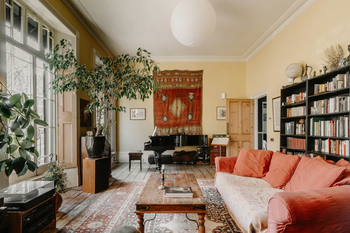 yellow living room raw wooden floorboards bookshelves large windows