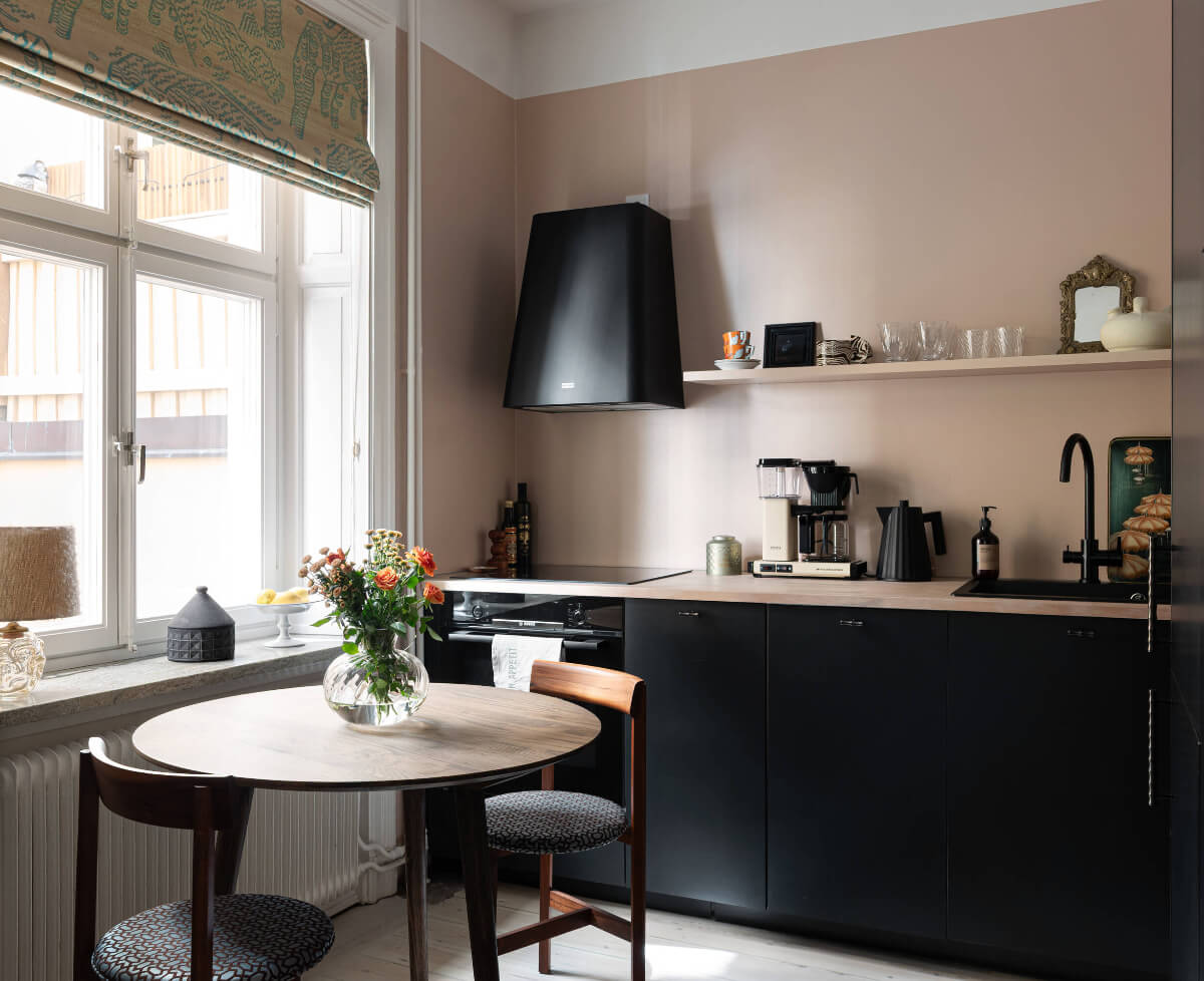 A Pink Studio Apartment with a Modern Black Kitchen 11 black kitchen cabinets pink walls round table