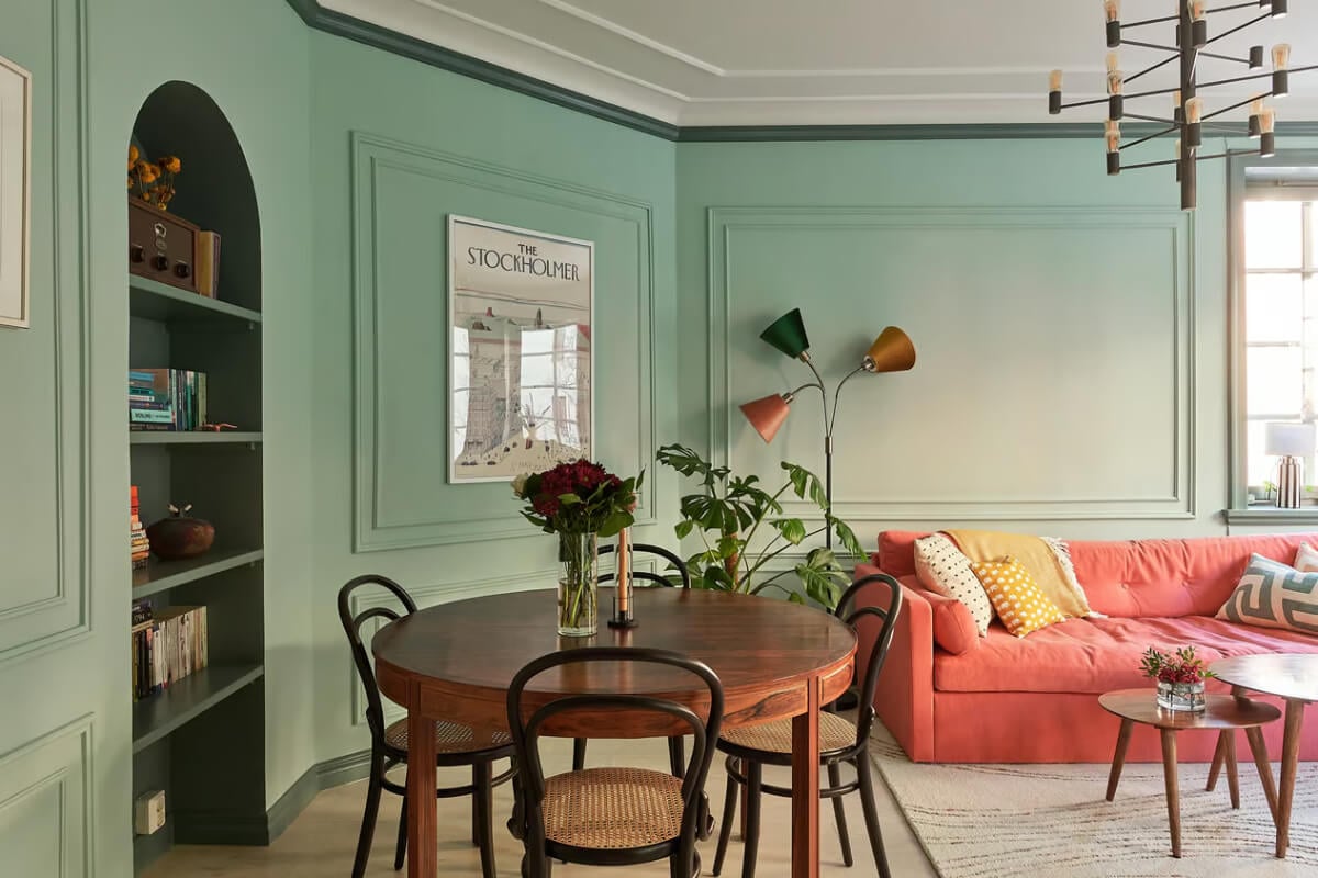 A Green Swedish Corner Apartment with an Open Floor Plan 6 green living room with round wooden table and pink sofa