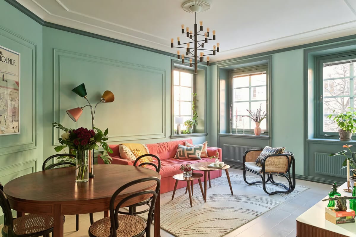 A Green Swedish Corner Apartment with an Open Floor Plan 1 pink sofa in green living room