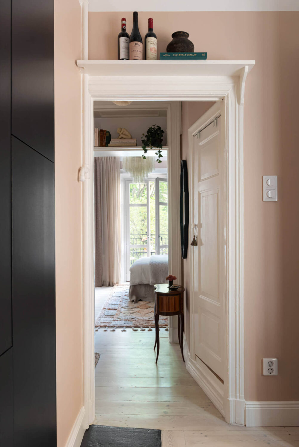 A Pink Studio Apartment with a Modern Black Kitchen 8 shelf above doorframe