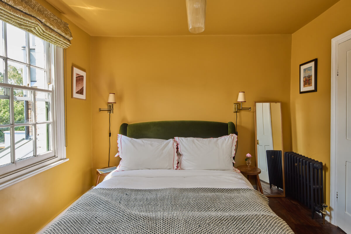 color-drenched yellow bedroom with green headboar