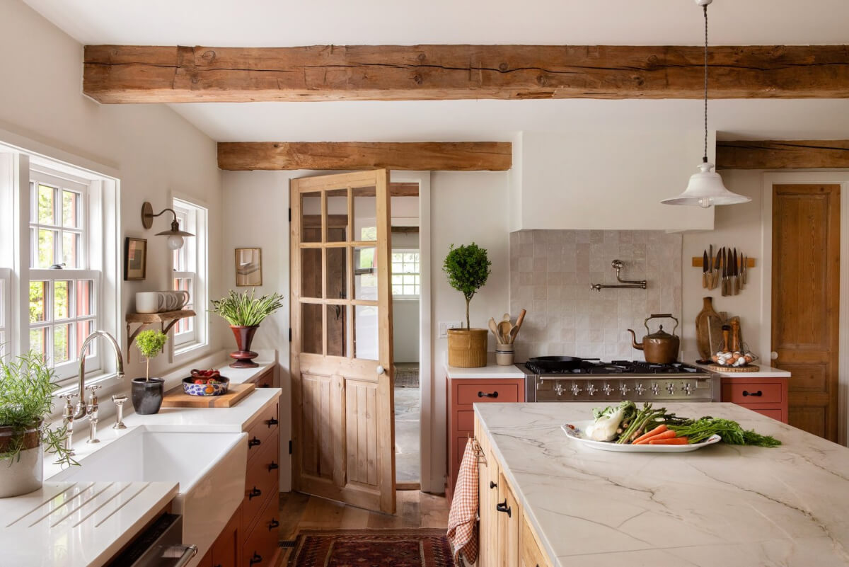butler sink under window terracotta colored cabinets