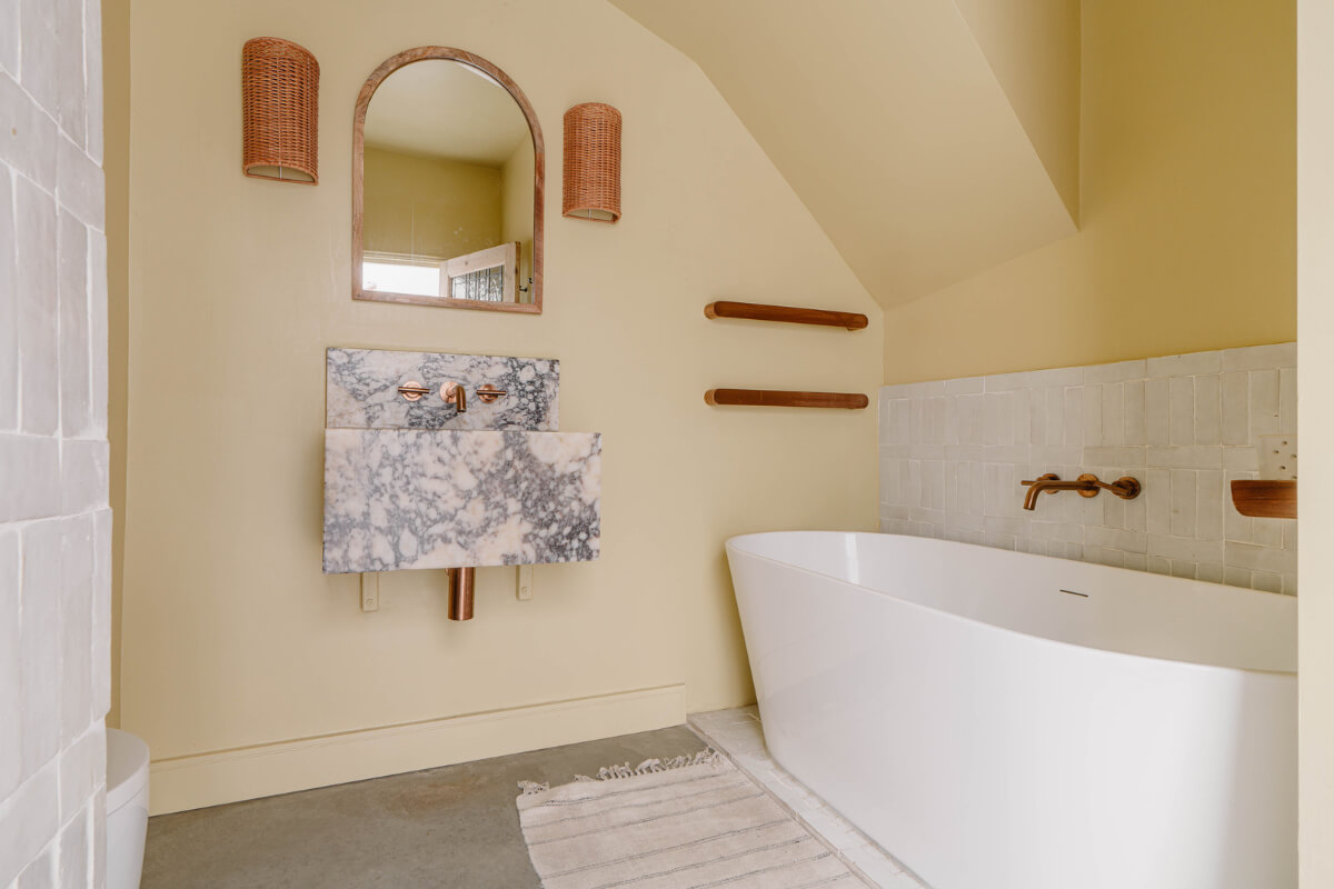 A Modern Ground-Floor Apartment with a Tiny Patio Garden 21 bathroom freestanding bath marble sink butter-yellow walls