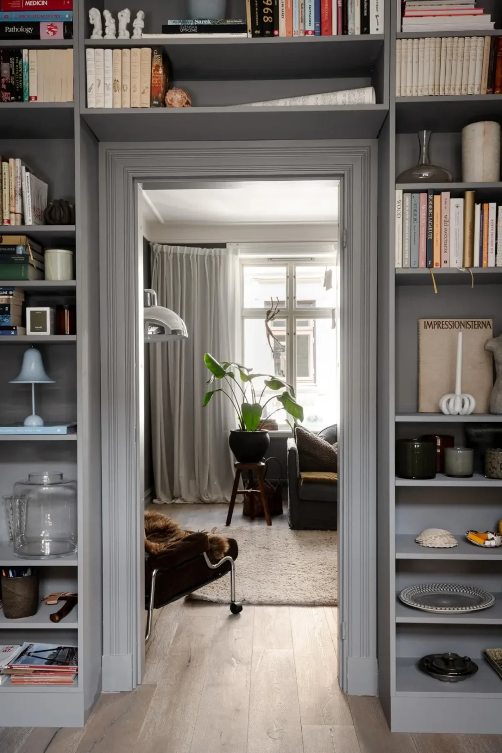 A Dark Gray Swedish Apartment with an Olive Green Kitchen 13 bookshelves around doorframe