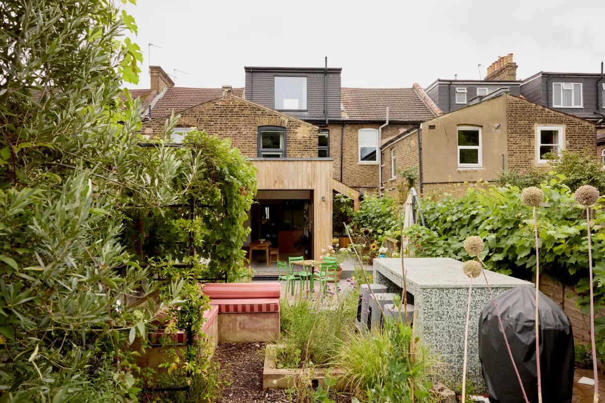 A Victorian Home with a Rich Color Palette and a Lush Garden 23 garden with terrace and built-in bench with pink cushions